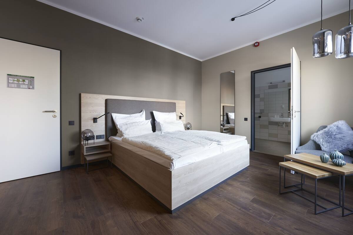 A modern bedroom with a wooden bed, a bedside table, a nightstand, and a mirror.