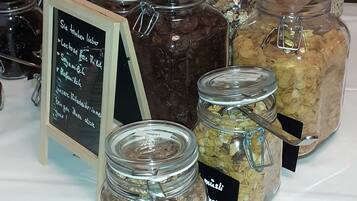 Een buffettafel met diverse etenswaren in glazen potten, waaronder plantaardige opties.