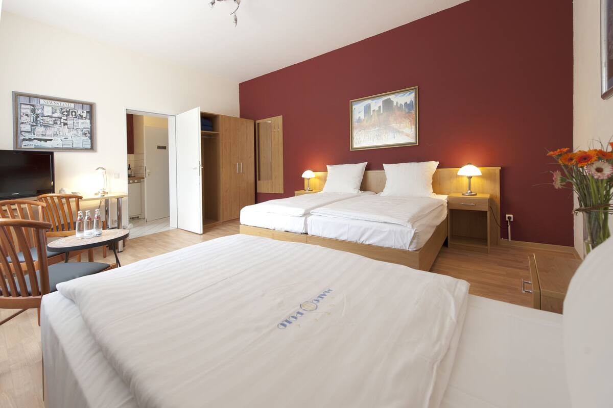 A hotel room with a large bed, a desk with a chair, a television, and a painting on the wall.