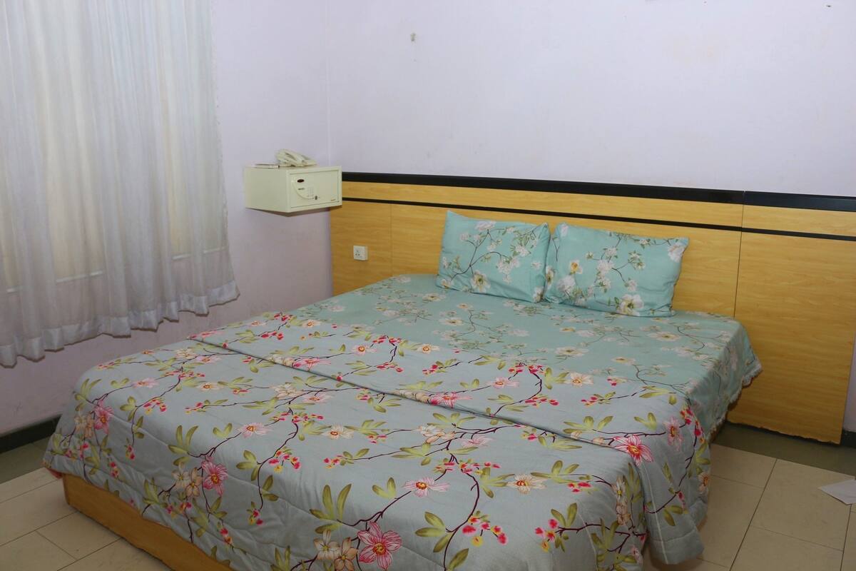 Un dormitorio con colcha de flores, cabecero de madera y teléfono junto a la cama.