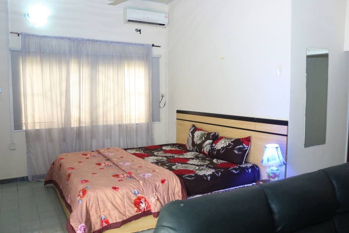 Un dormitorio con cama, mesita de noche, lámpara y ventilador de techo.
