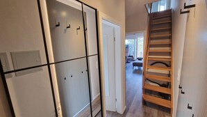 Un couloir au design moderne, avec un escalier en bois et une porte donnant sur un espace de vie.