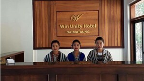 Una mesa de recepción en el Hotel Win Unity en Natmataung, con tres empleados.