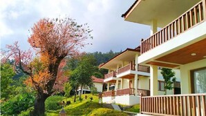 Un edificio de varios pisos con balcones y un árbol con flores rosadas en primer plano.