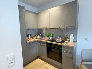 A modern kitchen with grey cabinets, a built-in oven, and a countertop with various kitchen items.