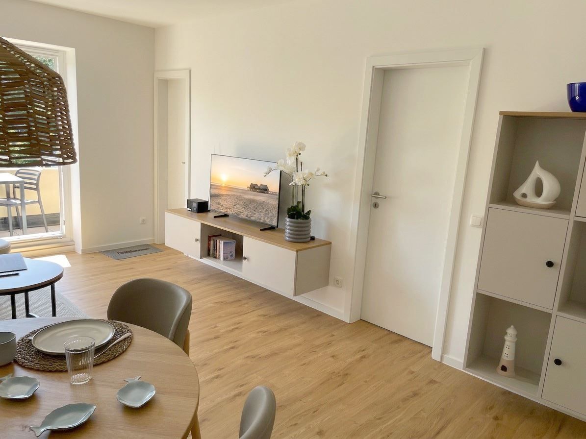Una sala de estar moderna con televisor, mesa de comedor y sillas.