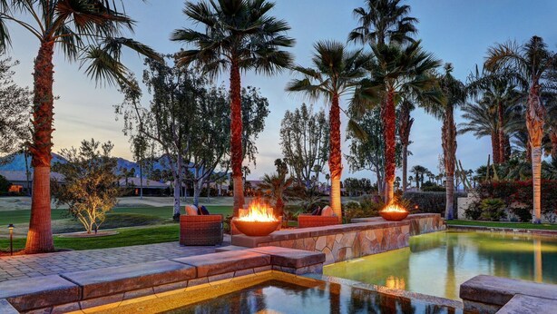 A landscaped outdoor area with a pool, fire pits, and palm trees. - Escape to Legends - Pool, Games & Amazing Mountain Views in PGA West #067651 5br (La Quinta)