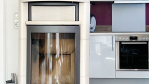 A modern kitchen with a built-in wood stove, a potted plant, and a calendar on the wall. - House Friesenperle - House Friesenperle Whg 01 (Sankt Peter-Ording)