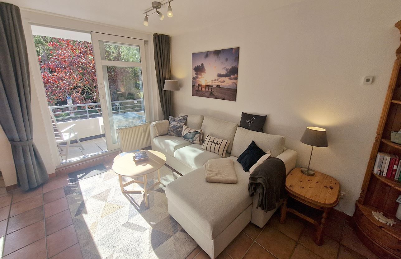 A living room with a sofa, a small table, a lamp, and a bookshelf.