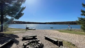 En campingplats vid sjön med picknickbord, en eldstad och en flagga.