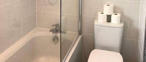 Une salle de bain avec une baignoire, des toilettes et une douche à parois de verre.