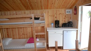 Un lit superposé avec un bureau et un petit réfrigérateur, le tout dans une pièce en bois.