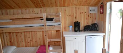 A bunk bed with a desk and a small refrigerator in a wooden room.
