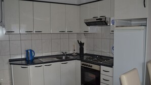 A kitchen with white cabinets, a black countertop, a stove, and a sink. - Apartments Kastilac (Kastela)