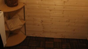 L’intérieur d’une cabane en bois, avec un mur en bois, une étagère en bois sur laquelle se trouve un panier, et une décoration murale en bois.