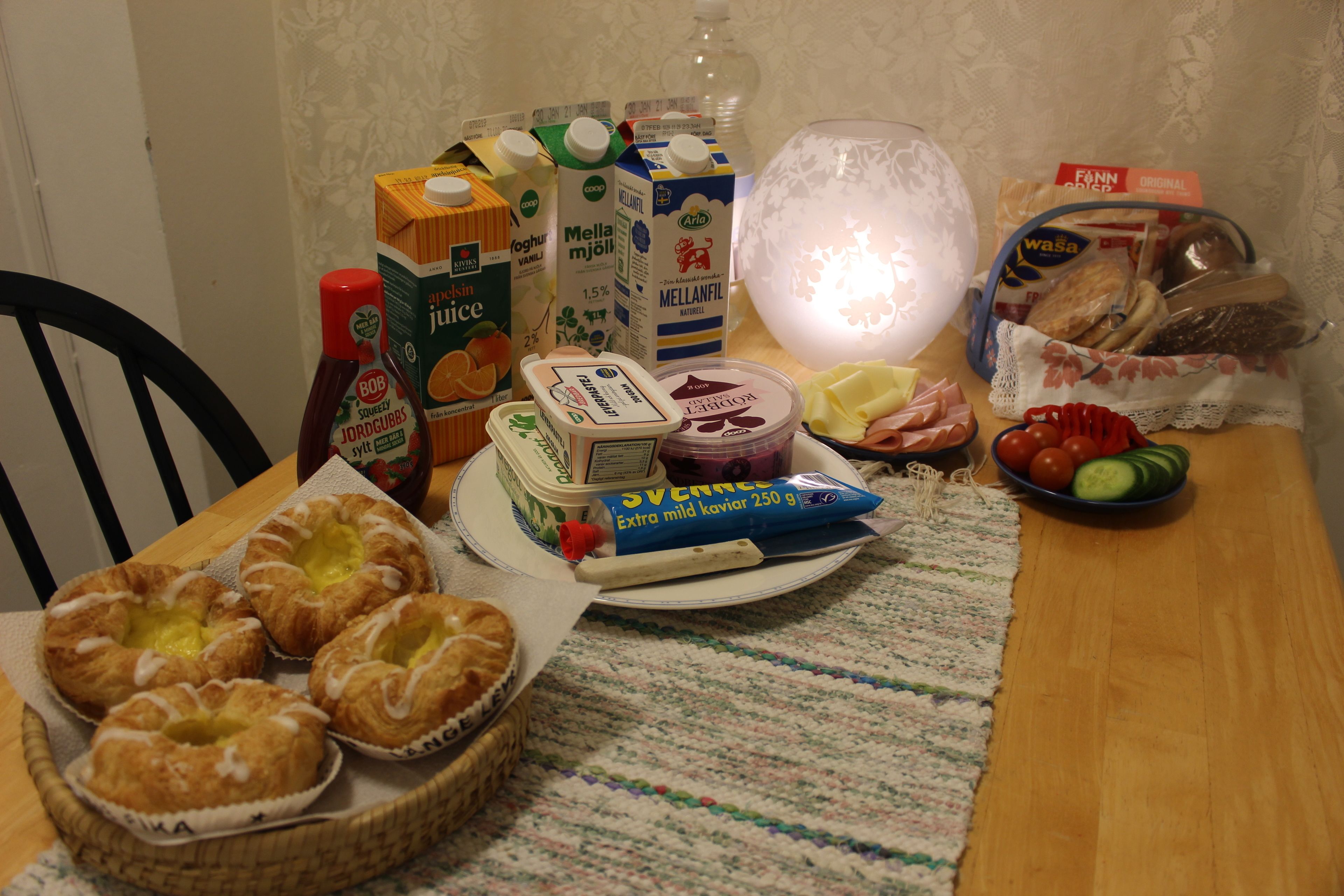 Una mesa con diversos alimentos, incluyendo pan, queso y una fuente de pasteles.