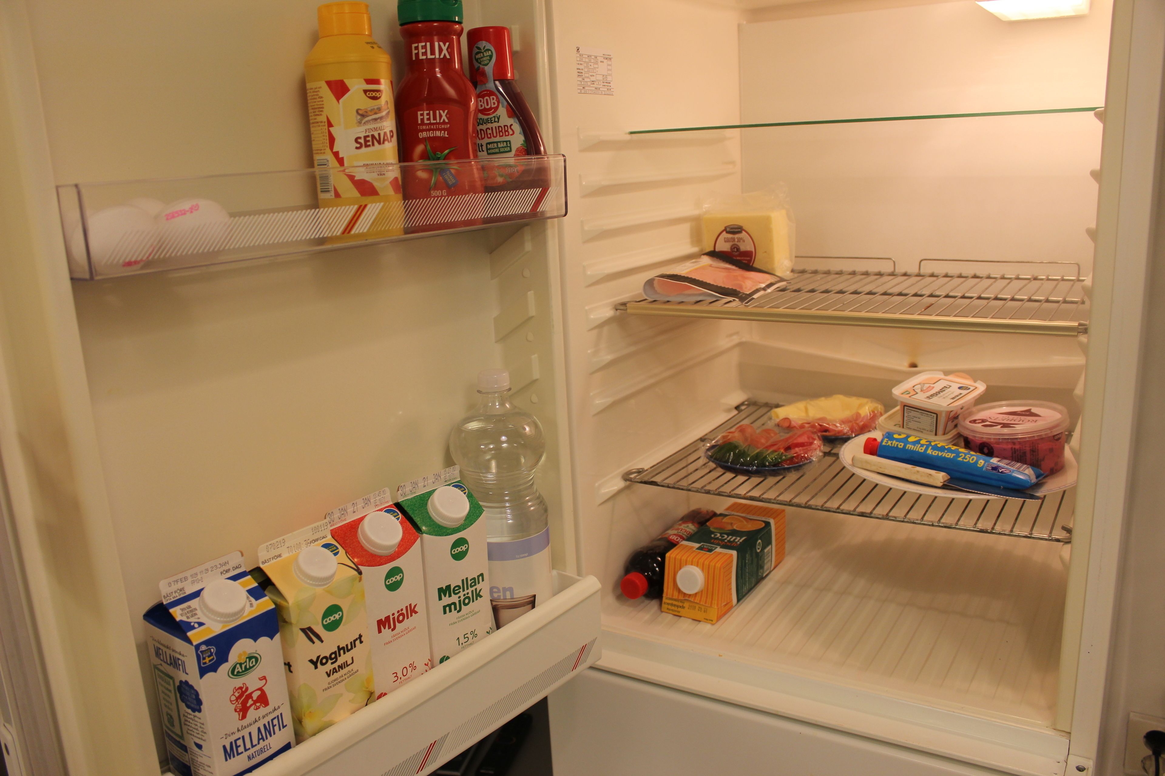 A refrigerator with shelves stocked with milk, juice, and condiments.