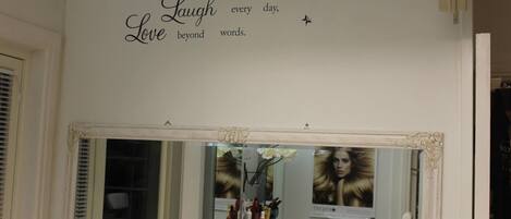 Una habitación con un espejo grande, un tocador con artículos de aseo y una cita inspiradora en la pared.