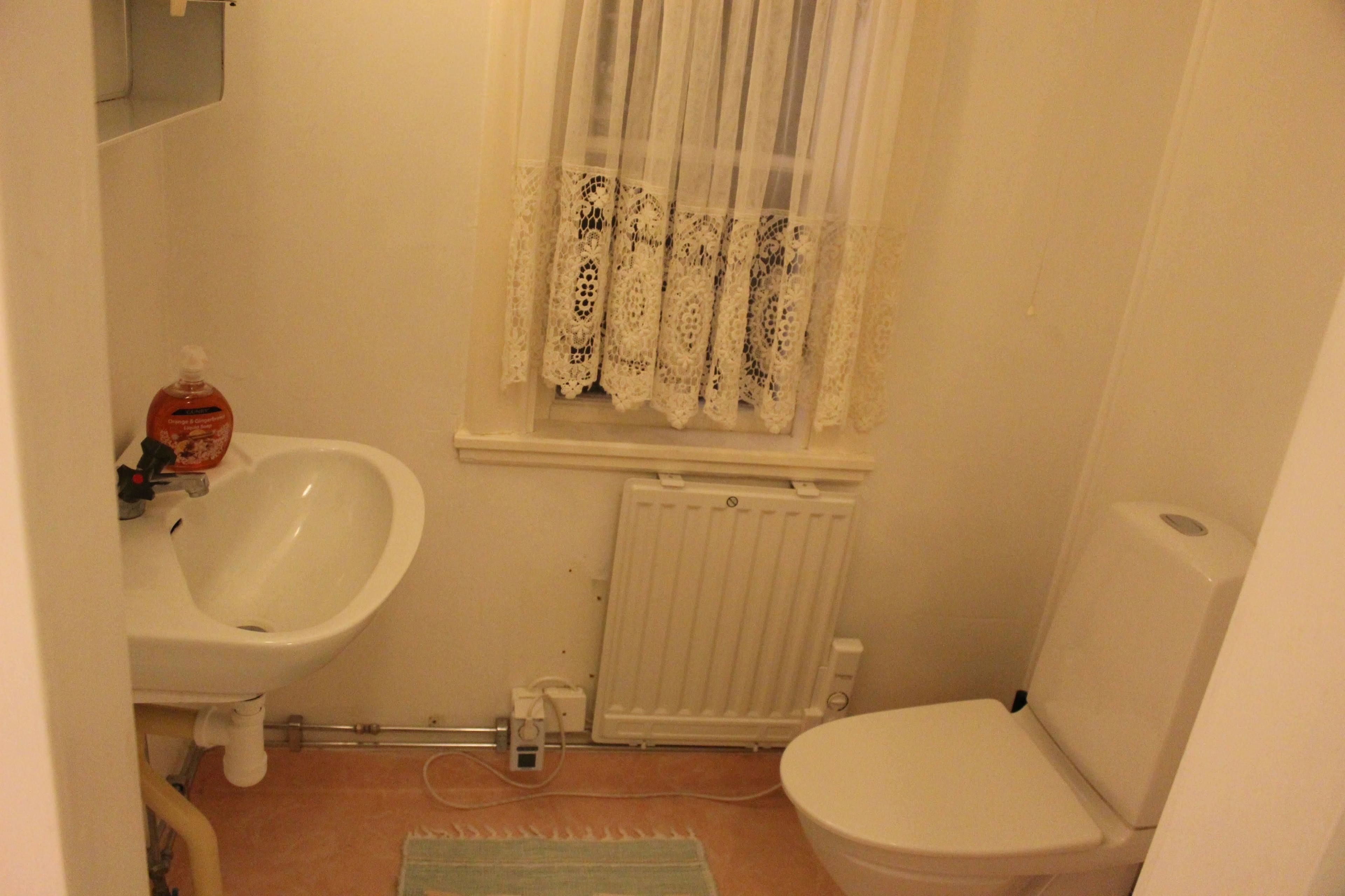 A small bathroom with a white sink, toilet, and radiator.