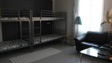Una habitación con literas, un sofá de cuero, una mesita de cristal y un taburete pequeño.