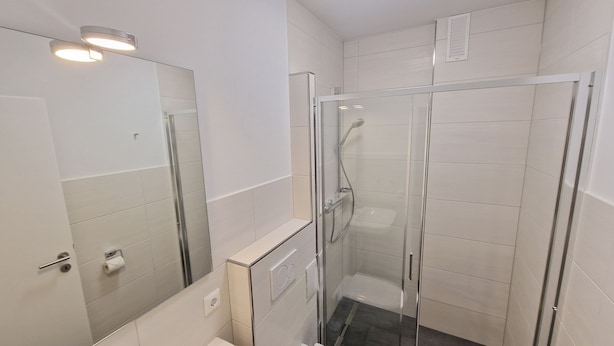 A modern bathroom with a glass-enclosed shower, a toilet, and a sink. - Haus Utlande - Haus Utlande Whg 10 (Sankt Peter-Ording)