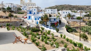A coastal village with white buildings, a church, and a road curving through the area. - Kimolos Houses (Kimolos)