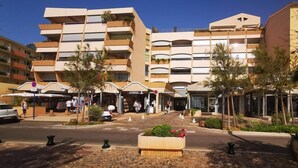 Ein modernes Hotel mit mehreren Balkonen, Sitzgelegenheiten im Freien und einem Kopfsteinpflasterplatz.