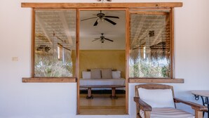 A room with a bed, a wooden chair, and a ceiling fan.