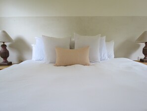 A neatly made bed with white bedding and a striped pillow, flanked by two lamps on wooden nightstands. - Villa Gardenia - Casa Cactus by the sea (Todos Santos)