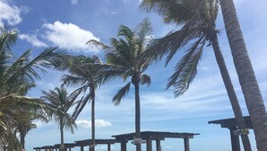 A beachside walkway with palm trees, wooden gazebos, and a view of the sea. - Locanda Dei Venti (Itarema)