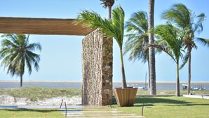 A pathway leading to a stone wall with palm trees and a beach in the background. - Locanda Dei Venti (Itarema)