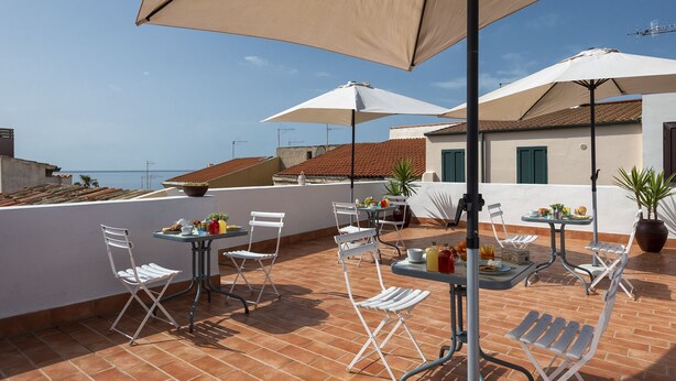 Terraza en la azotea con asientos exteriores, incluyendo mesas y sillas, bajo grandes sombrillas.