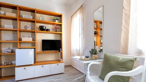 Una sala de estar moderna con un sofá blanco, un mueble de televisión de madera y un ventanal con cortinas.