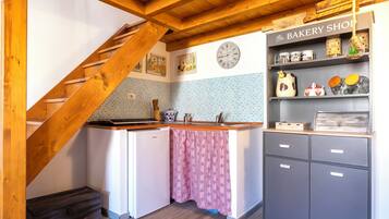 Una cucina con una scala in legno, un orologio, un'insegna di panetteria e uno schienale piastrellato.