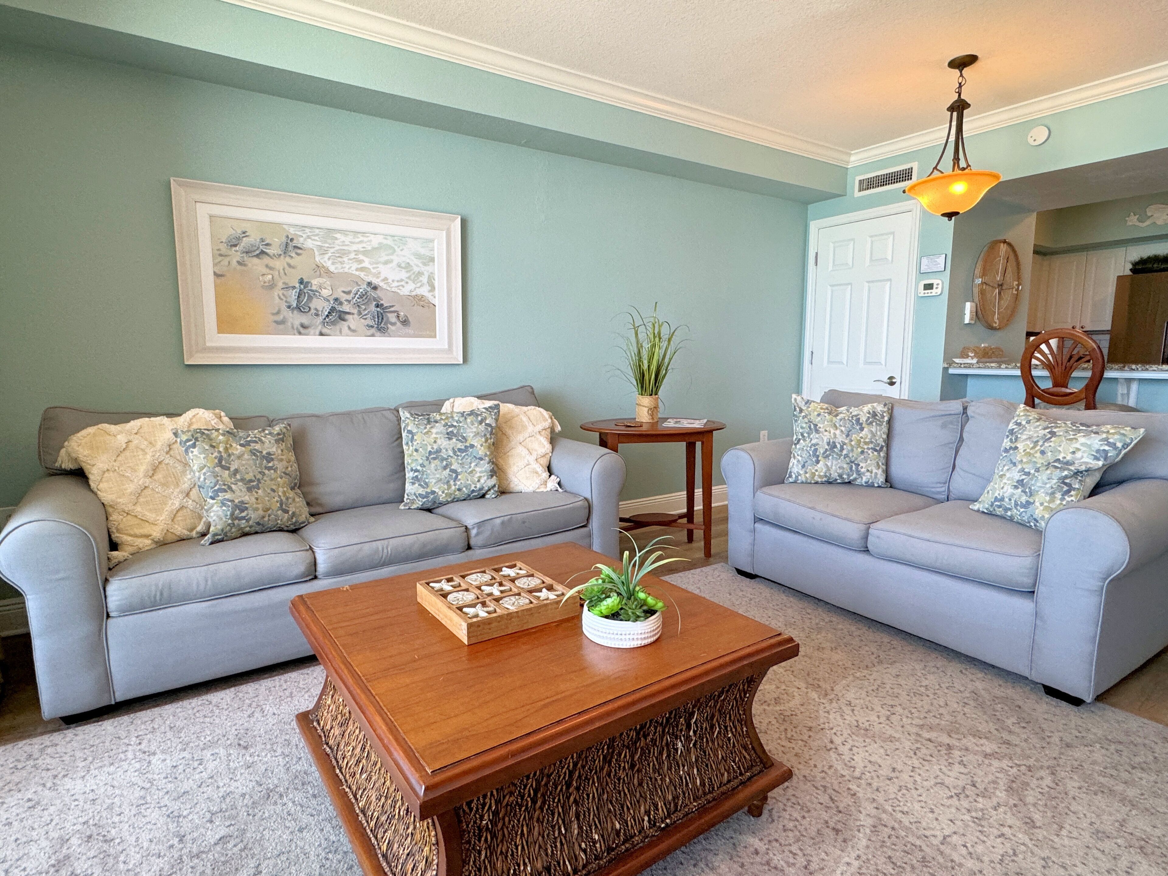 A living room with two grey sofas, a wooden coffee table, and a framed artwork on the wall.
