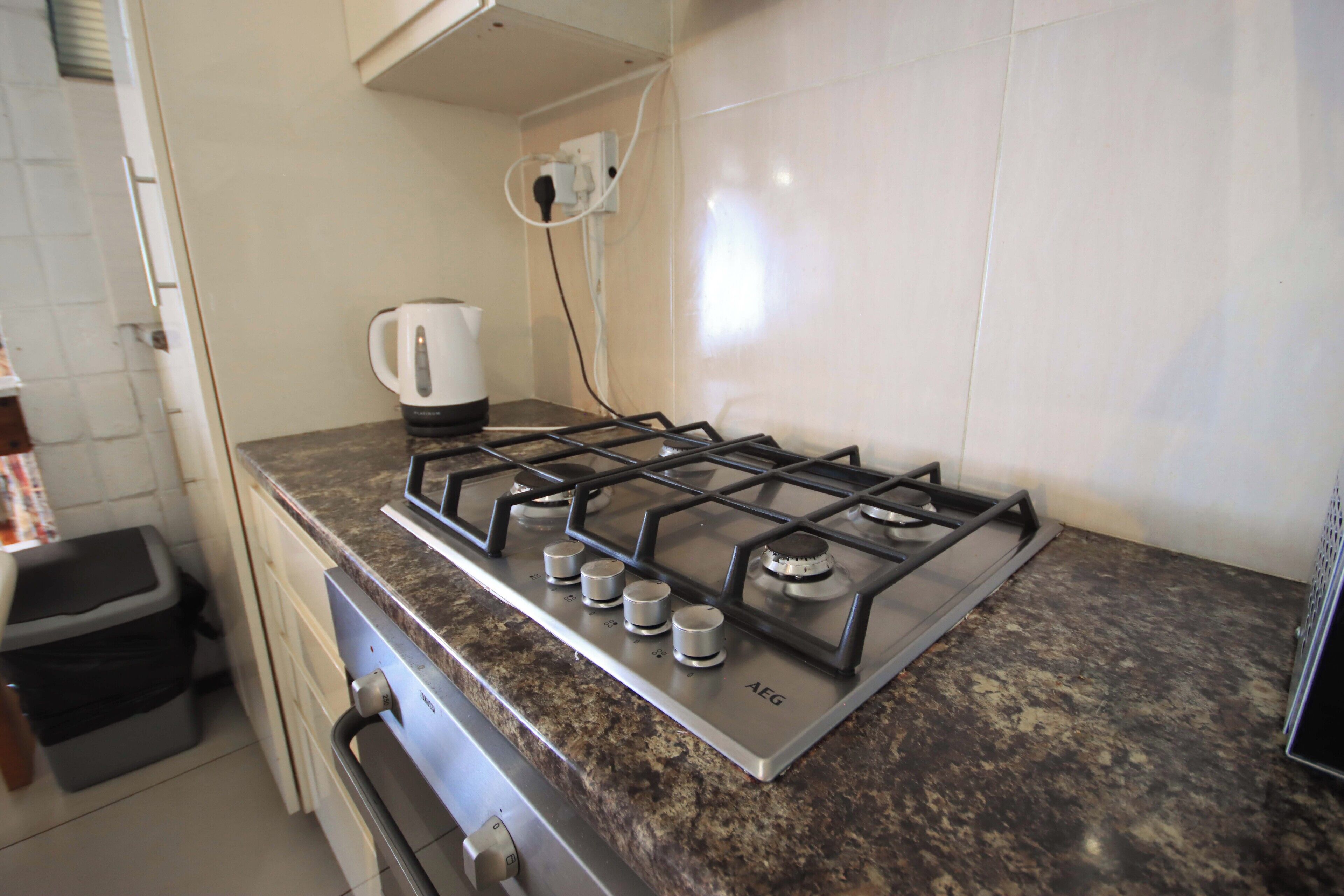 A kitchen with a gas stove, oven, and a coffee maker on the counter.