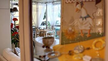 A room with a bed, a window with curtains, a table with chairs, and a wall with a duck illustration.