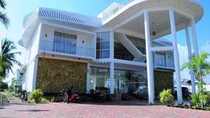 A modern two-story building with a curved balcony, large windows, and a central staircase. - Sunstar Nilaveli (Nilaveli)
