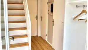 A staircase with wooden steps leading to a landing, a white door, and a hallway with a wooden floor.