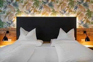 A double bed with white linens, a dark headboard, and two bedside lamps.