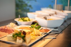 A buffet table with various food items and utensils.