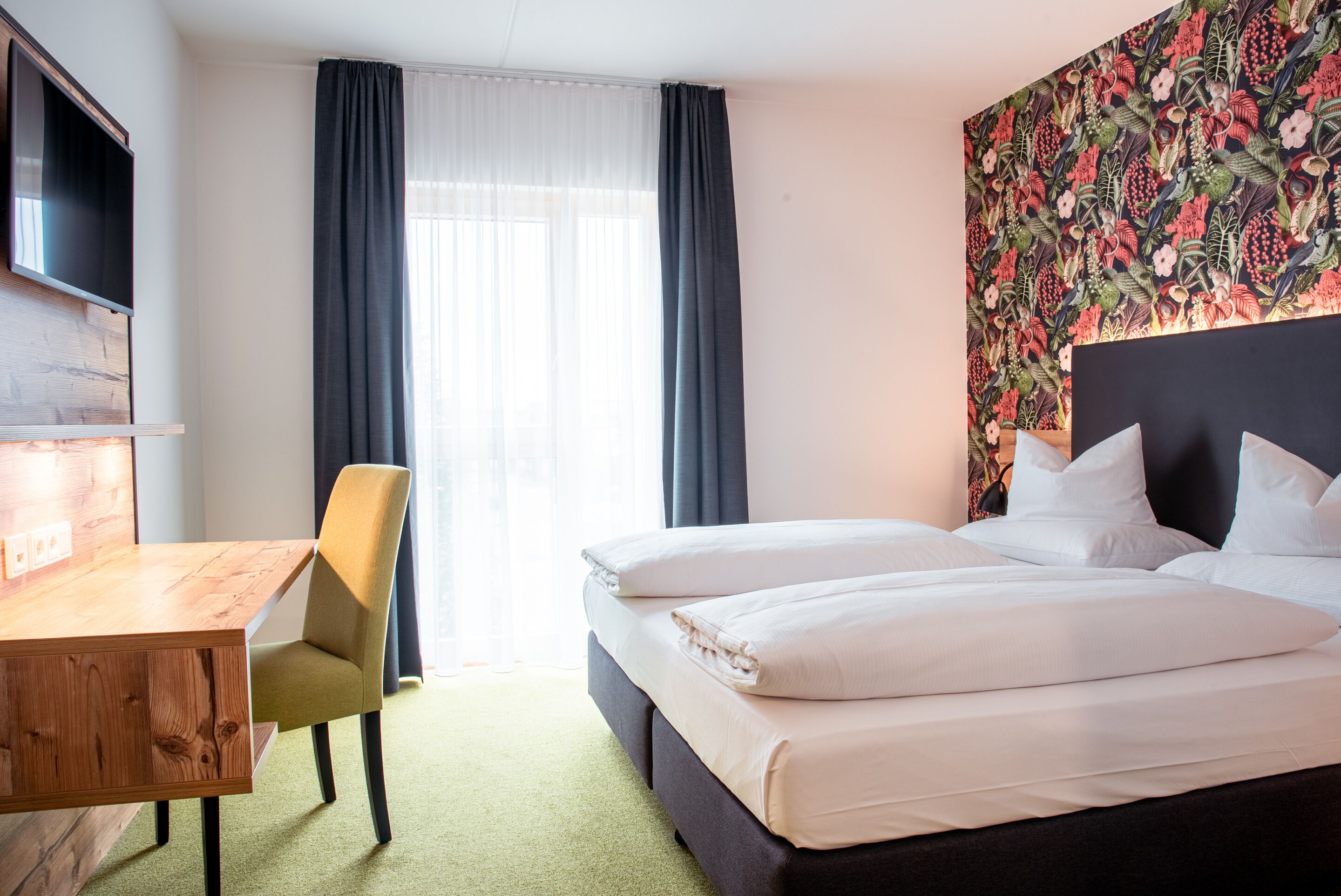A hotel room with a bed, a desk, and a chair.