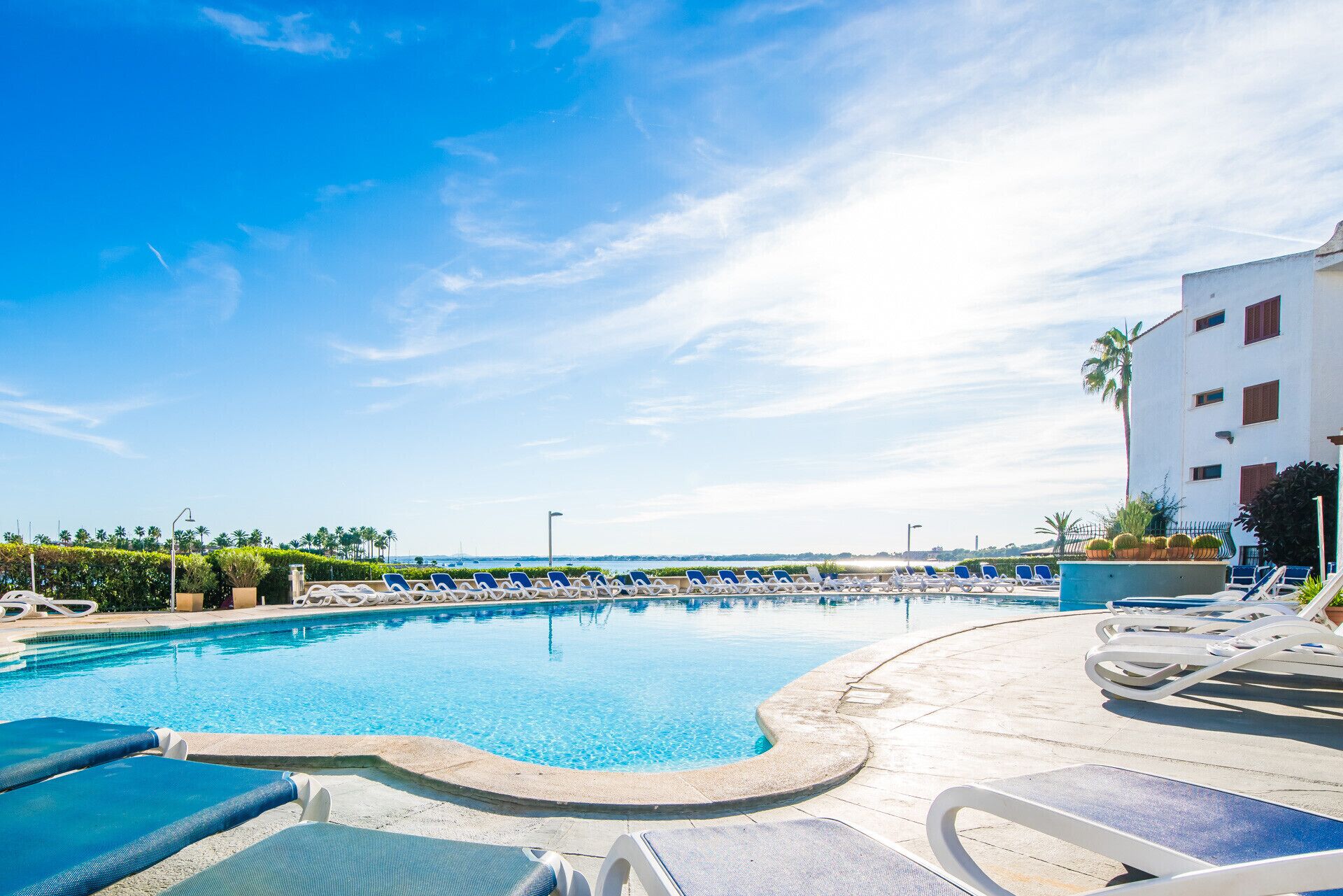 A pool area with lounge chairs and a building in the background.