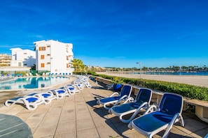 Un espace aménagé au bord de la piscine, avec des chaises longues, et un bâtiment en arrière-plan.