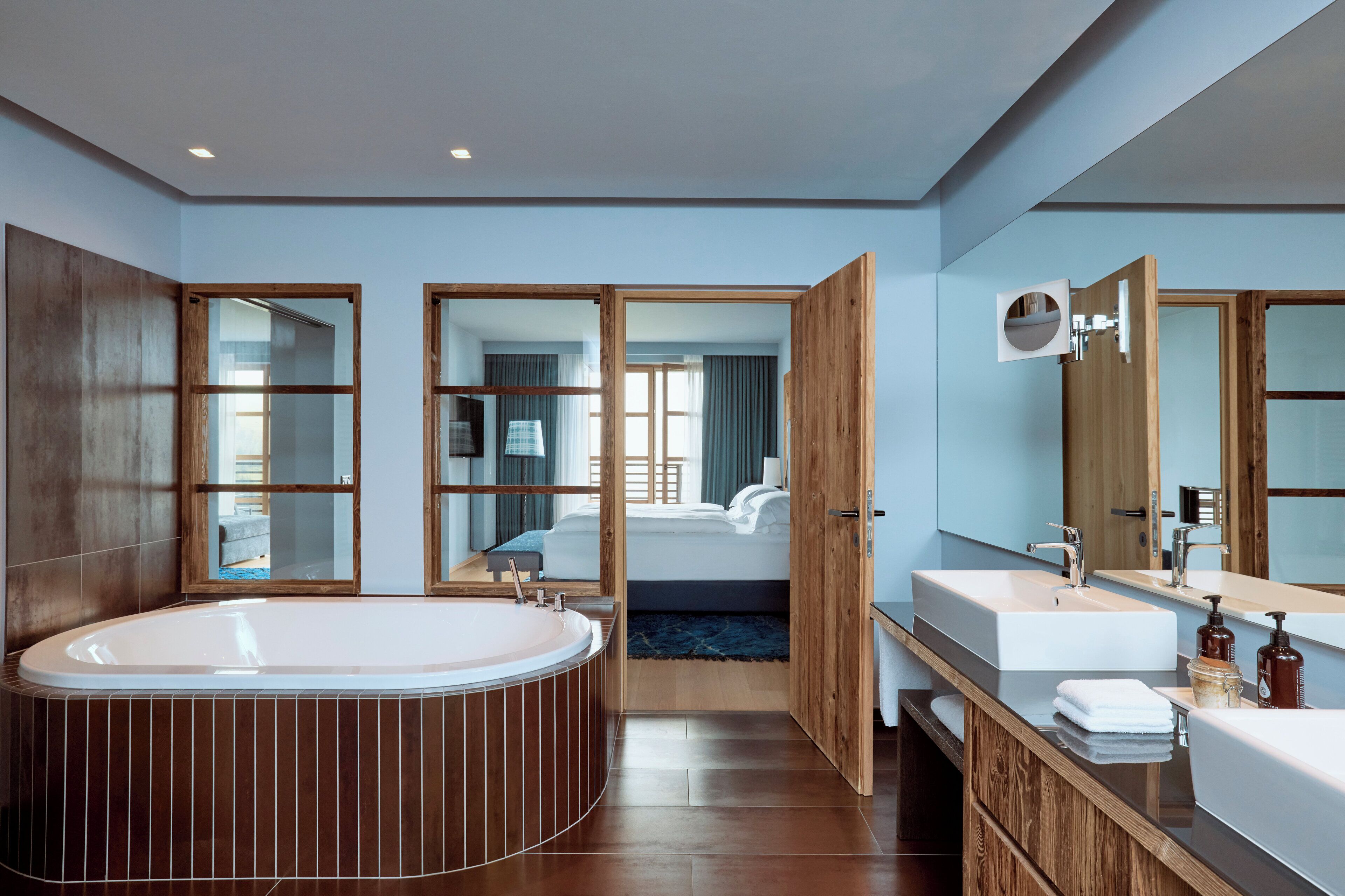 Ein modernes Badezimmer mit einer großen Badewanne, zwei Waschbecken und einem Spiegel.