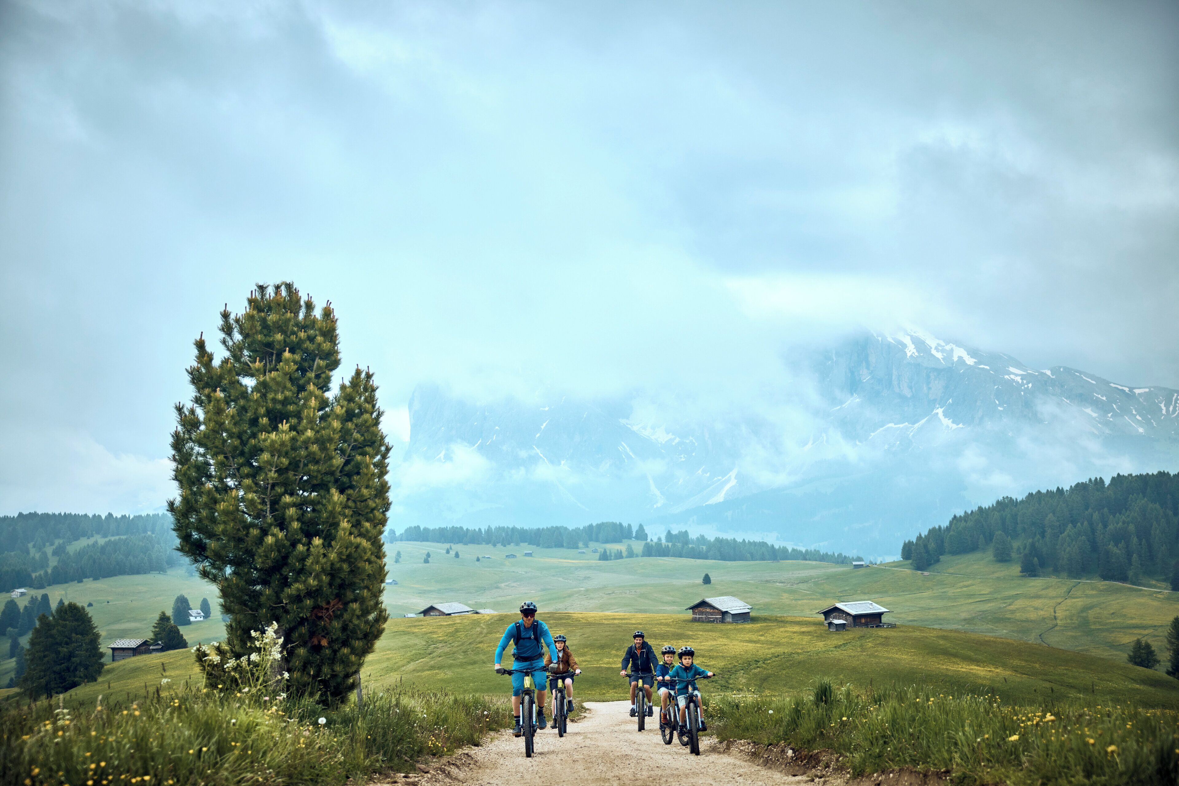 Eine Gruppe Radfahrer auf einem Feldweg, im Hintergrund ein Berg.
