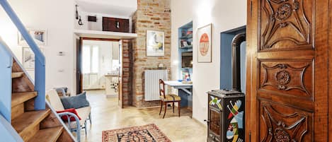 A spacious living area with a staircase, a wooden cabinet, and a kitchen in the background.