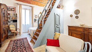 A living room with a staircase, a sofa, a wooden cabinet, and a bookshelf. - Acqui Terme - Via Manzoni 5 (Acqui Terme)