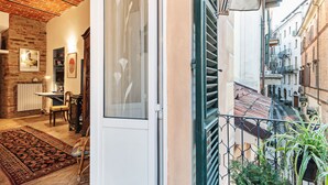 A cozy interior with a brick ceiling, a dining area with a table and chairs, and a view of a narrow street with buildings. - Acqui Terme - Via Manzoni 5 (Acqui Terme)