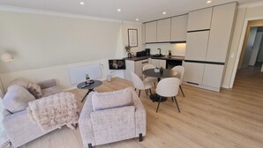 Een modern appartement met een zithoek, eettafel en kitchenette.